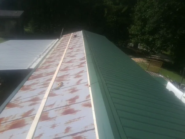 Old rusted panels beside newly installed green metal roofing — Wind Damage Roof Repair by Roofing Brothers in Hilton