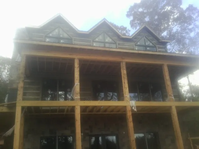 Dormers and porch framing on a large log home under construction — Roof Coating work by our crew in Hilton
