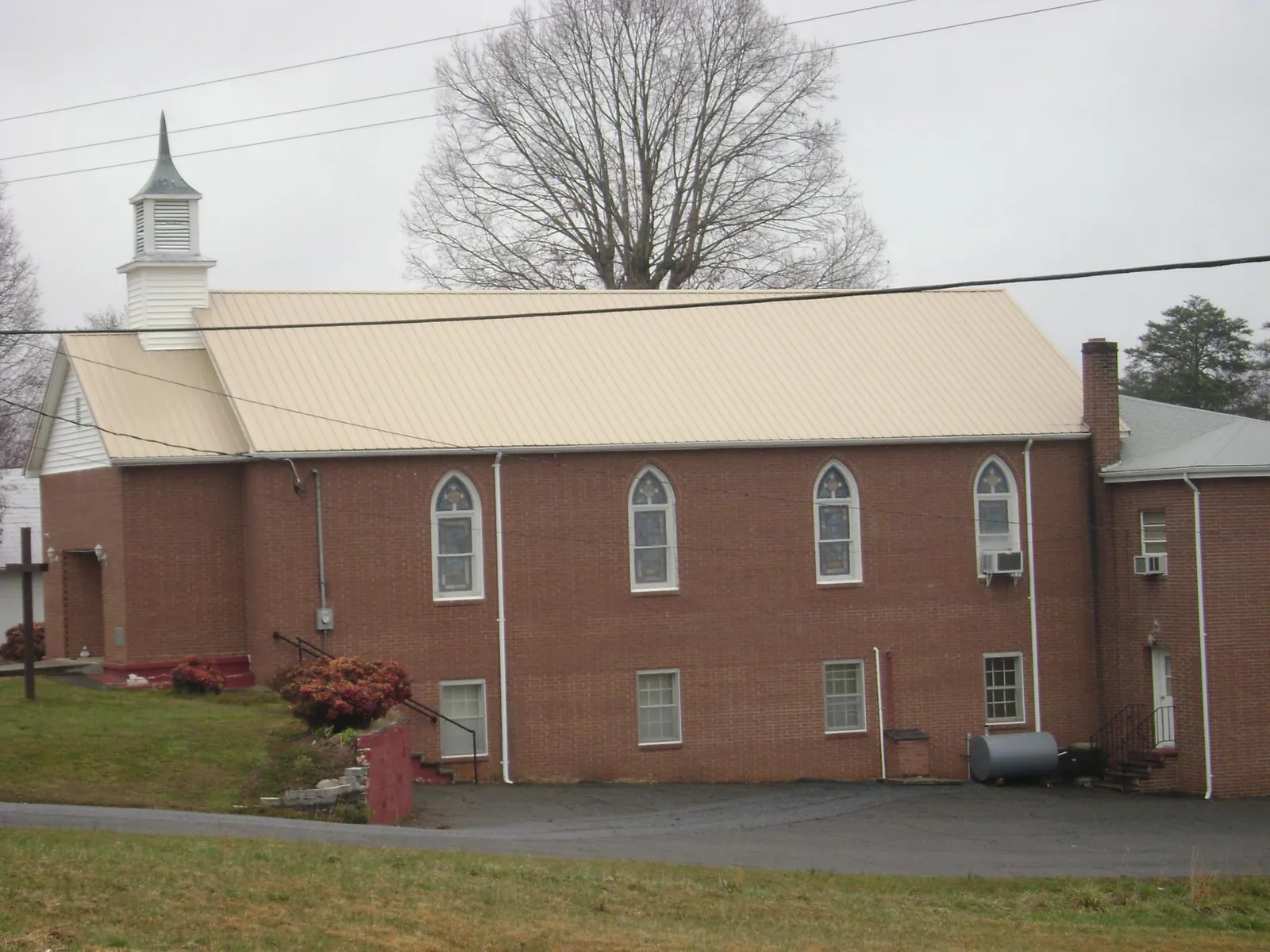 New tan metal roof on a brick church with a white steeple in Hilton