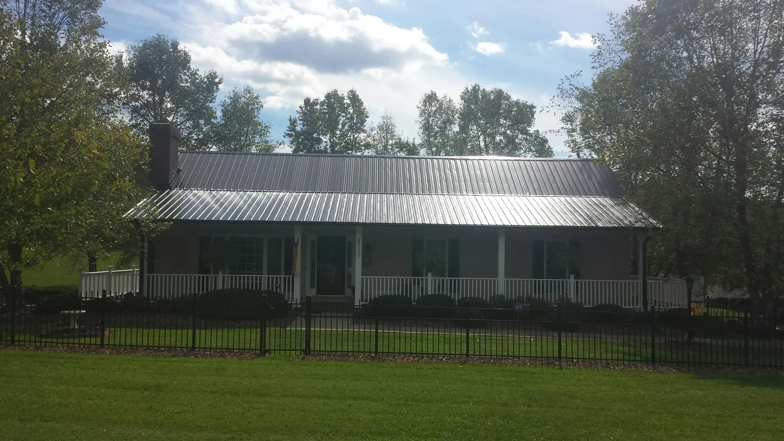 Gray metal roof on a brick ranch with a full width front porch — Gutter Guard Installation work by our crew in Hilton