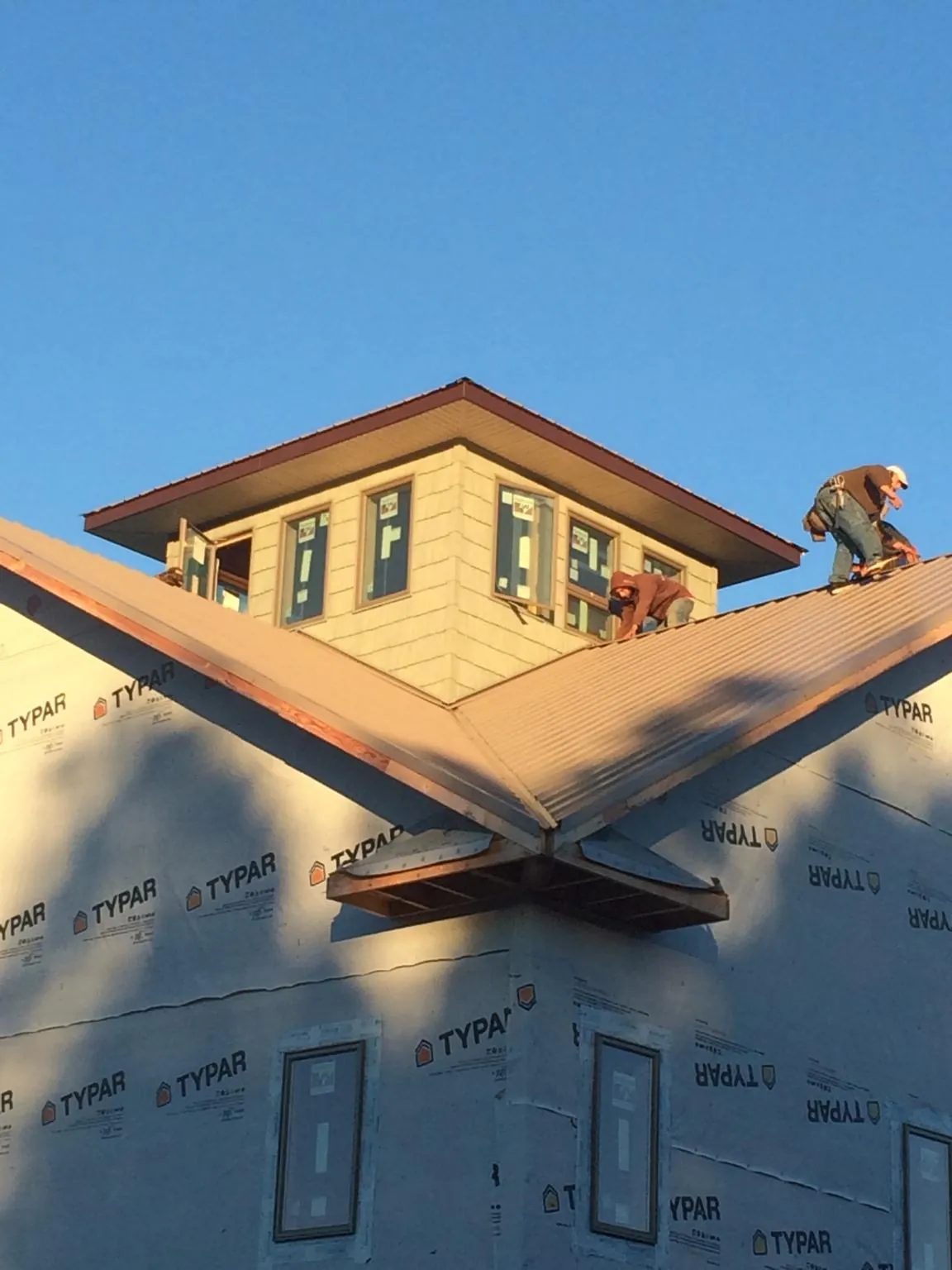 Roofers working around a rooftop cupola on a new metal roof at sunset — Roof Waterproofing in Hilton by Roofing Brothers